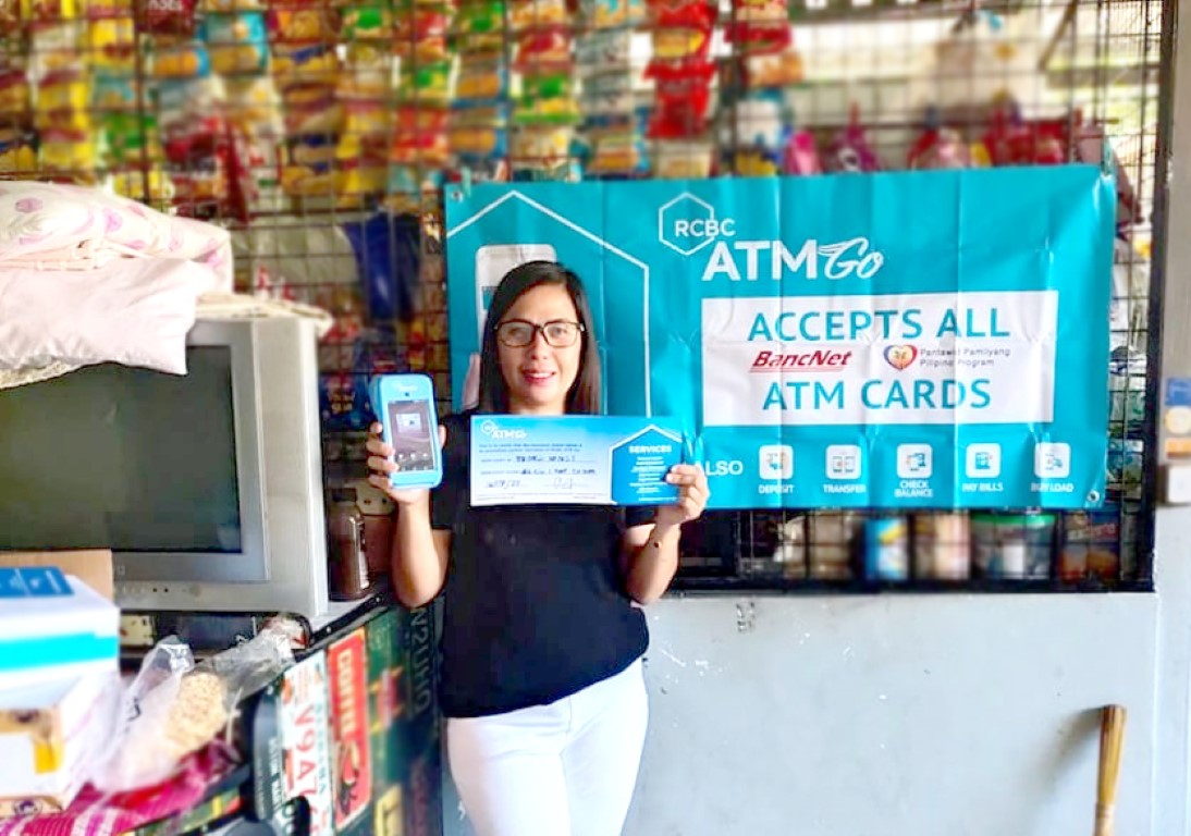 A shop-owner in the Philippines using an RCBC ATM Go terminal inside a neighbourhood sari-sari store.